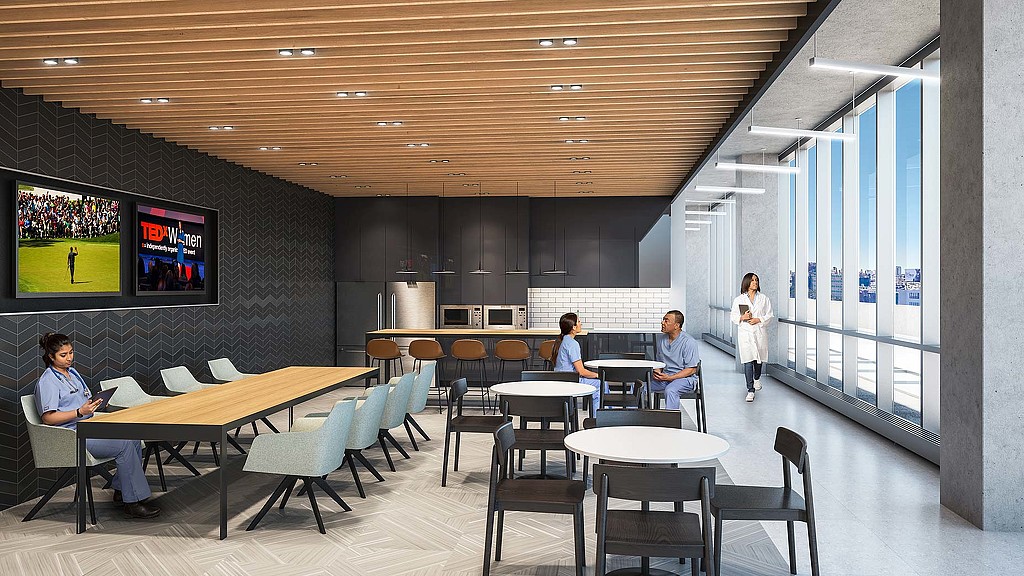 A group of people sitting at tables in a room with large screens.